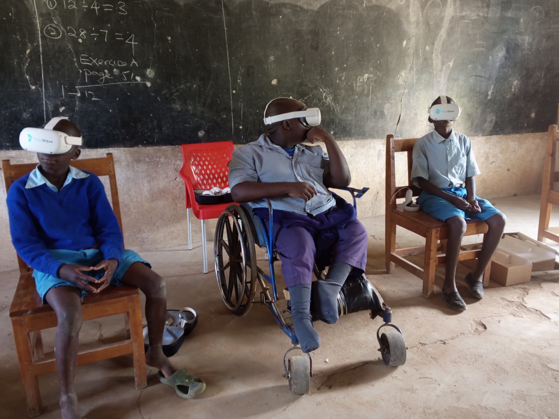Pupils in a Makueni classroom, one of them in a wheelchair, taking part in a lesson using headsets